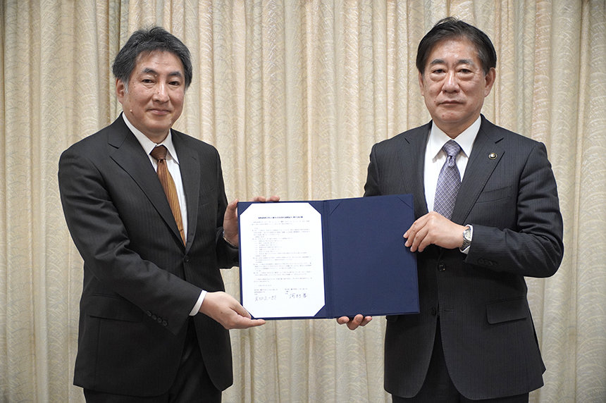 Mayor of Mitaka Takashi Kawamura (right) and ICU President Shoichiro Iwakiri, holding up the letter of agreement together.